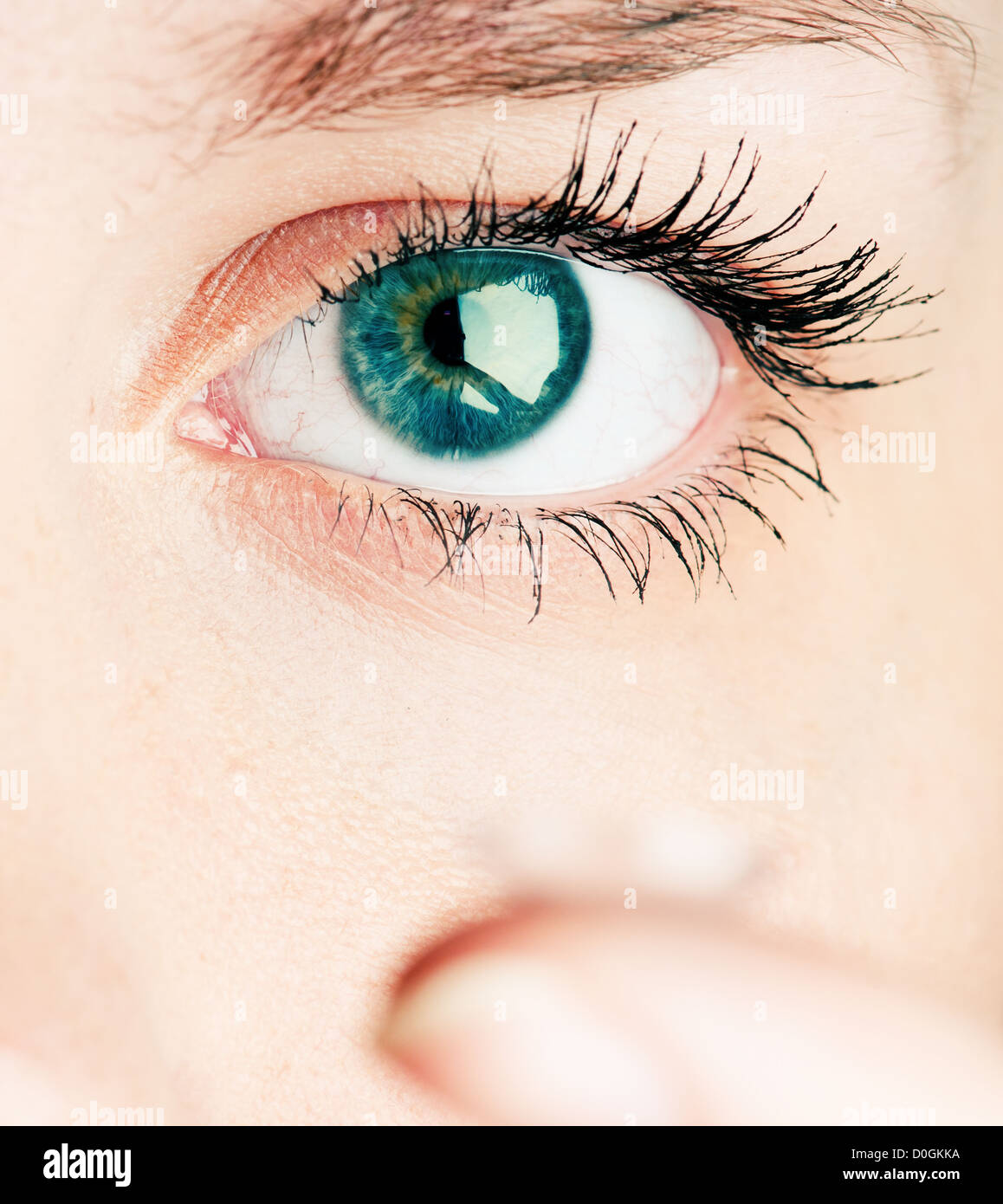 Cerca de la inserción de una lente de contacto en el ojo femenino Foto de stock