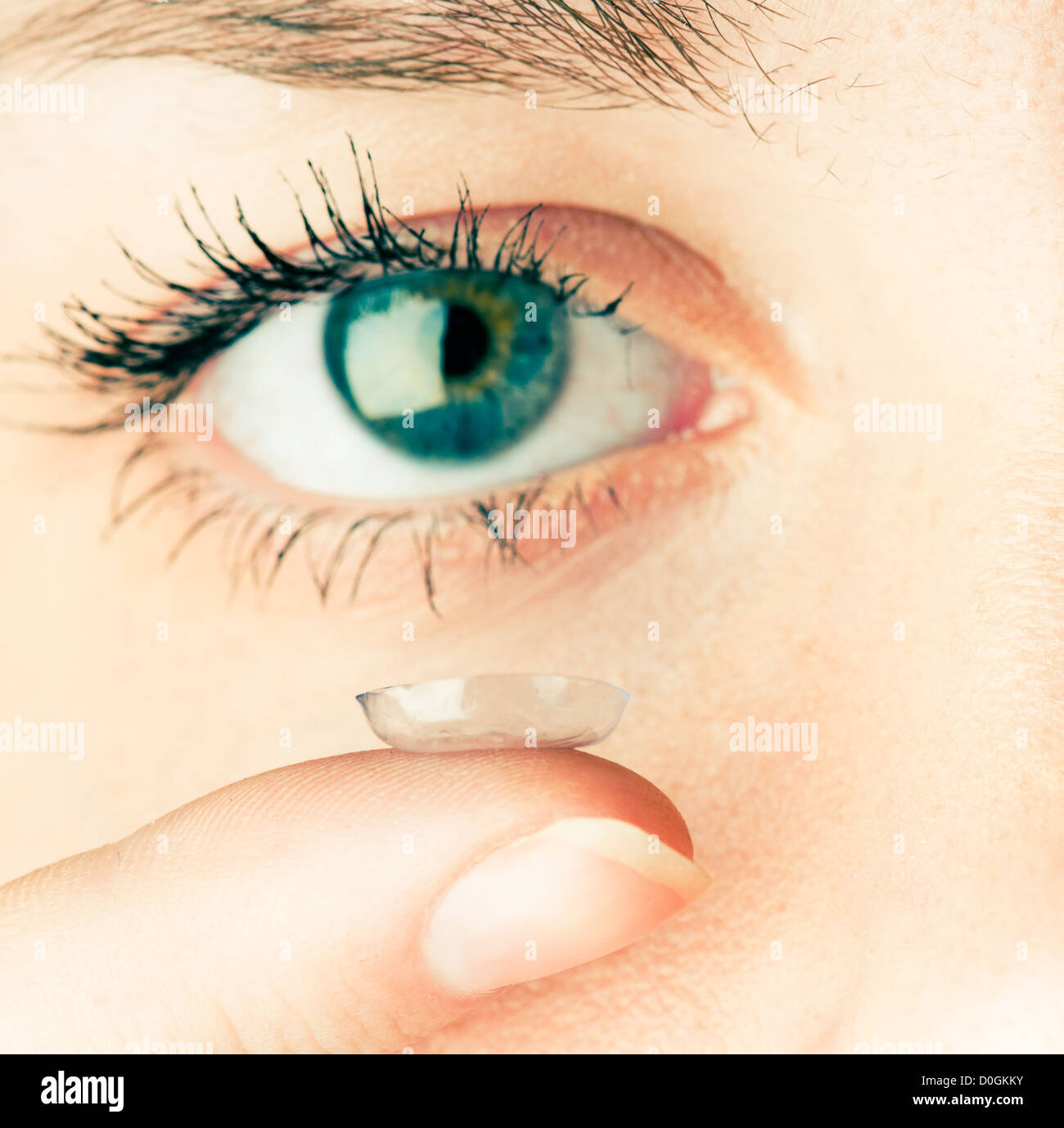 Cerca de la inserción de una lente de contacto en el ojo femenino Foto de stock