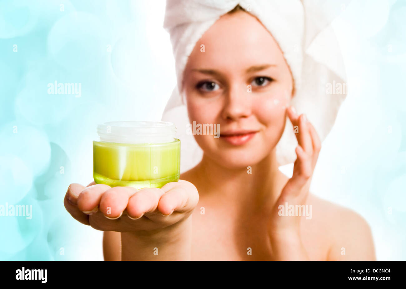 Bella mujer en toalla aplicar crema después del baño con luces en el fondo Foto de stock