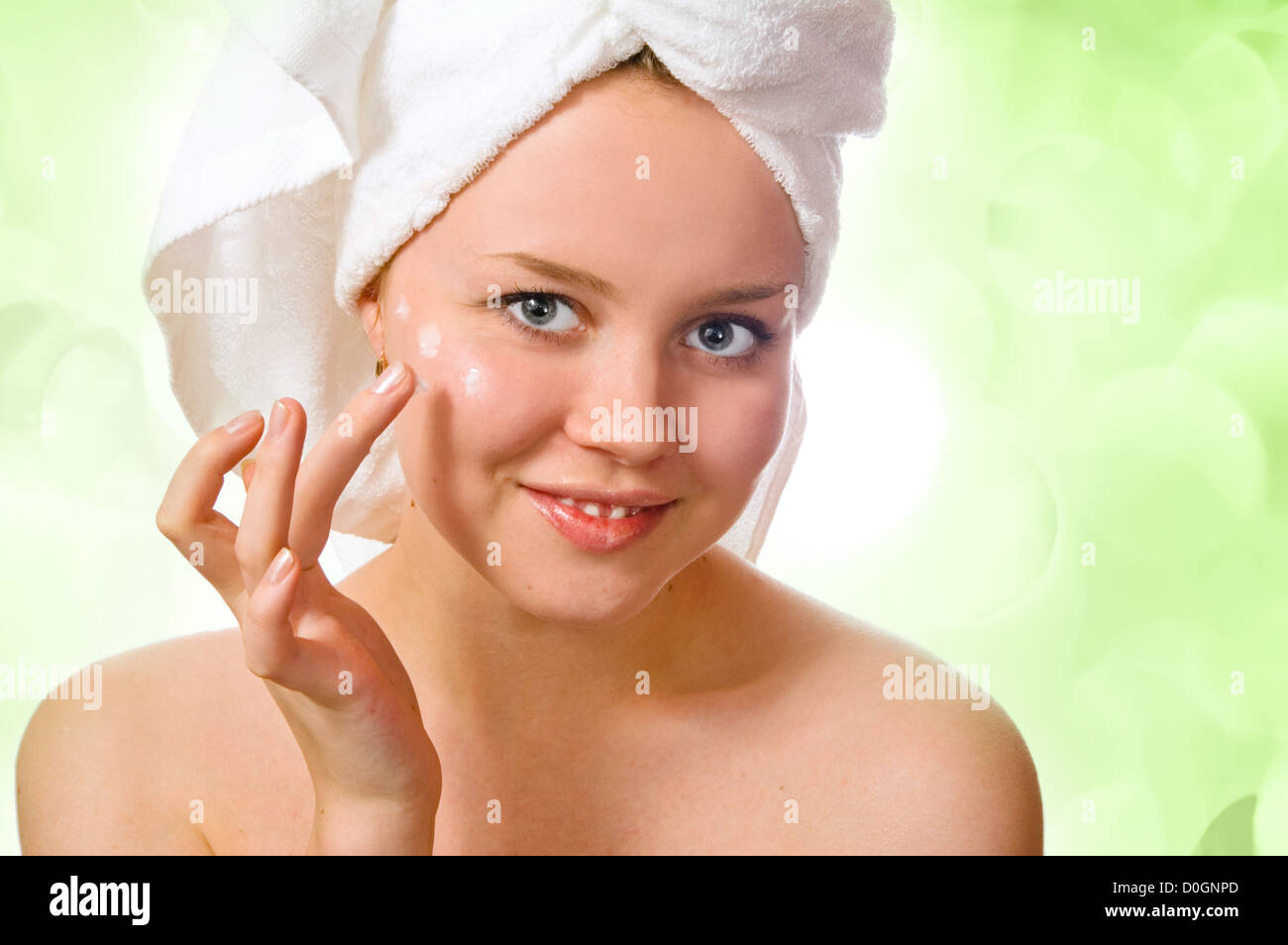 Bella mujer en toalla aplicar crema después del baño con luces en el fondo Foto de stock