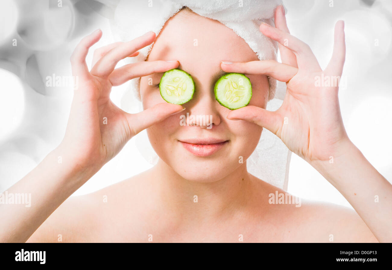 Mujer con pepinos en los ojos con luces en el fondo Foto de stock