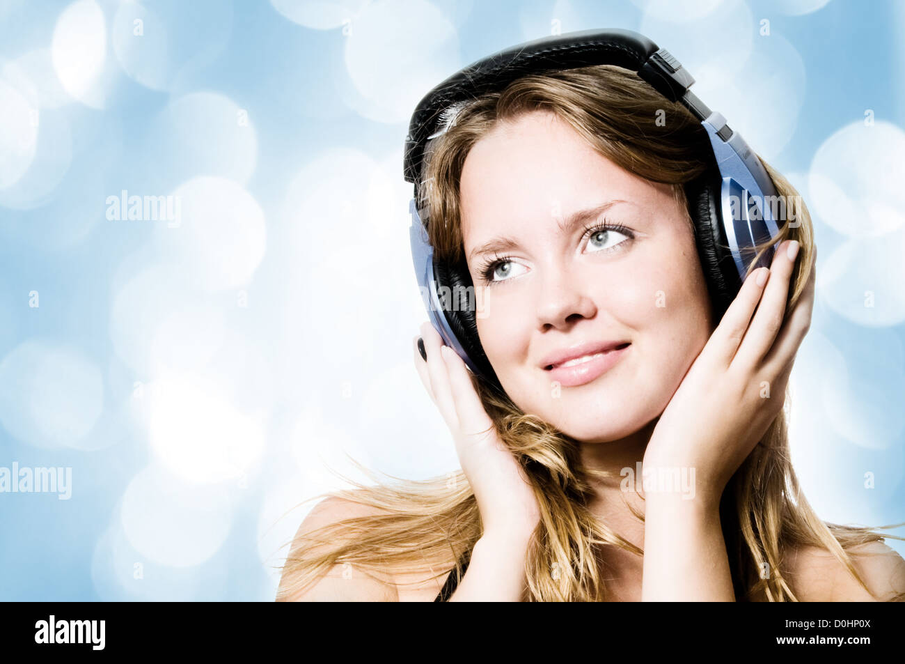 Hermosa niña escuchando música con luces azules en el fondo Foto de stock