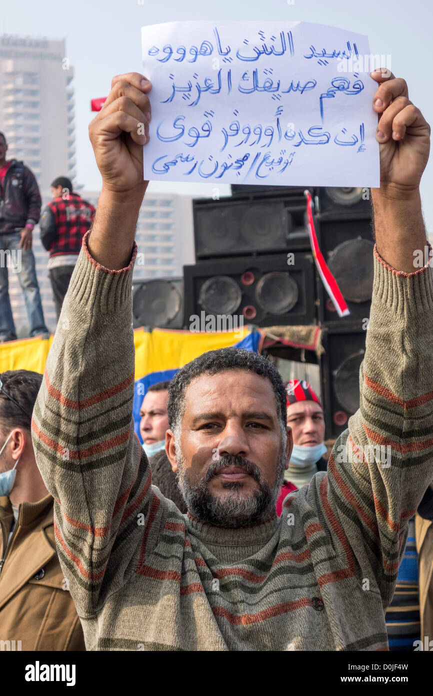 El 27 de noviembre de 2012. Un demostrador de las protestas contra el Presidente Morsi la asunción de poderes absolutos en la plaza Tahrir, El Cairo, Egipto, sosteniendo un cartel en árabe que dice 'Mr Netanyahu, hacer su querido amigo entiendo que es todo". Foto de stock