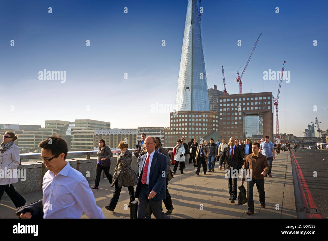 Los viajeros caminando al trabajo sobre el puente de Londres con el Shard edificio del fondo. Foto de stock