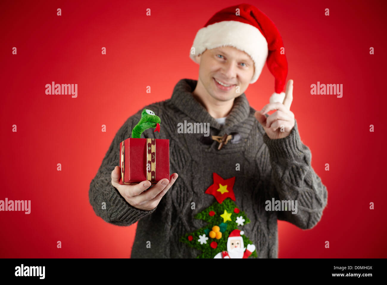 Retrato del hombre feliz en Santa cap celebración juguete serpiente en giftbox abierto Foto de stock