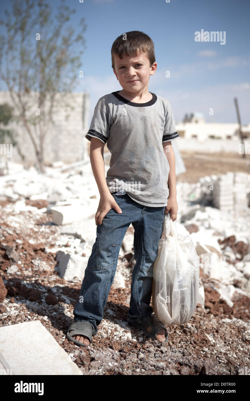 5/10/12, Azaz, Siria. Un joven obtiene suministros para su familia, deteniéndose además los restos de bombardear casas dañadas. Foto de stock
