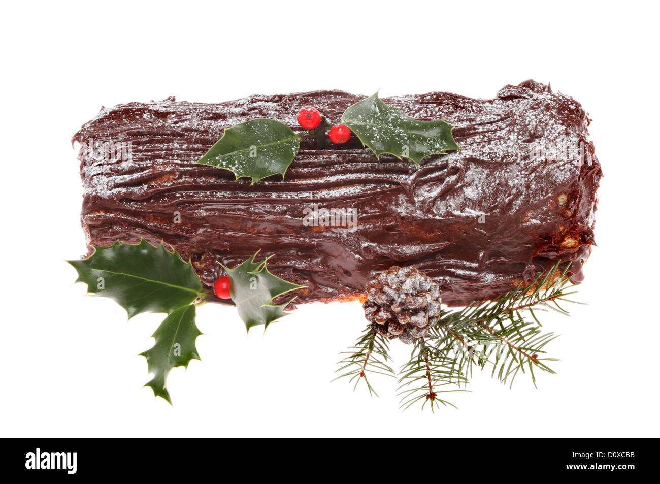 Yule log de chocolate decorada con holly, cono de pino y abeto y hojas Foto de stock