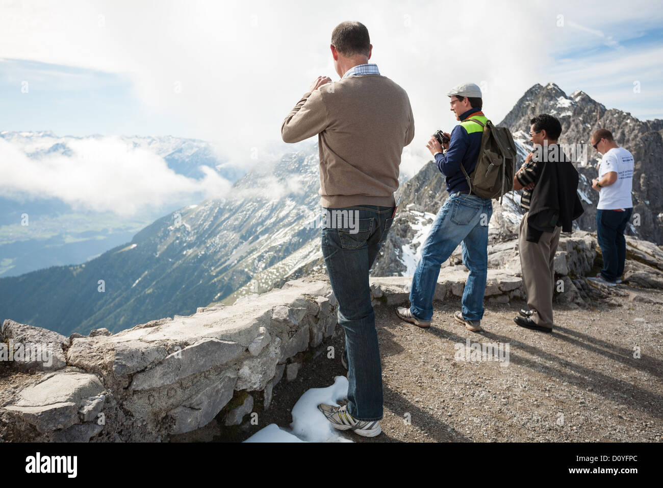 En el Hafelekar pico en los Alpes por encima de Innsbruck turistas parado en el borde y tomar fotos de las vistas del valle de abajo. Foto de stock