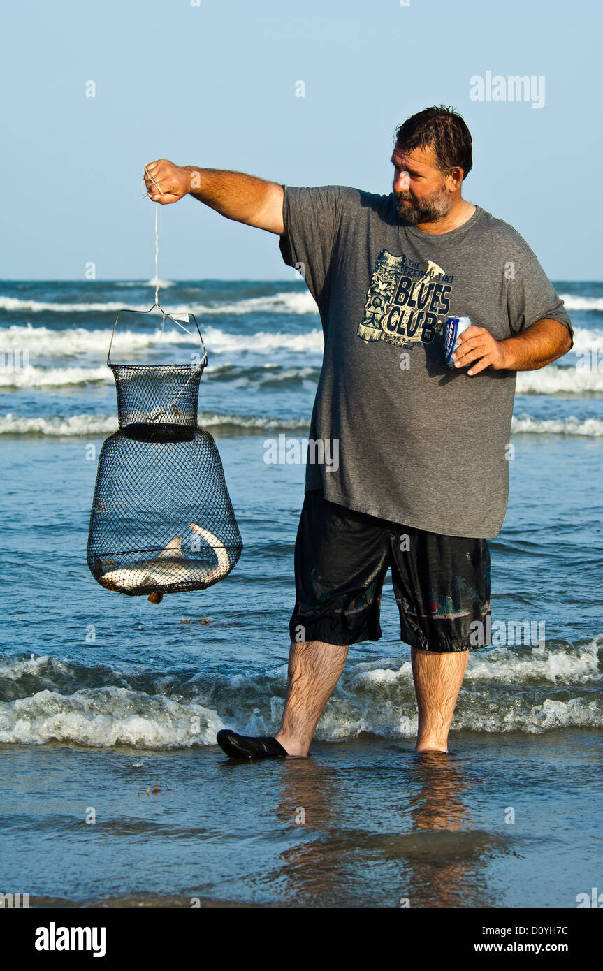 Hombre sujetando una cesta de pescado en vivo con un tiburón en Port Aransas Texas Foto de stock