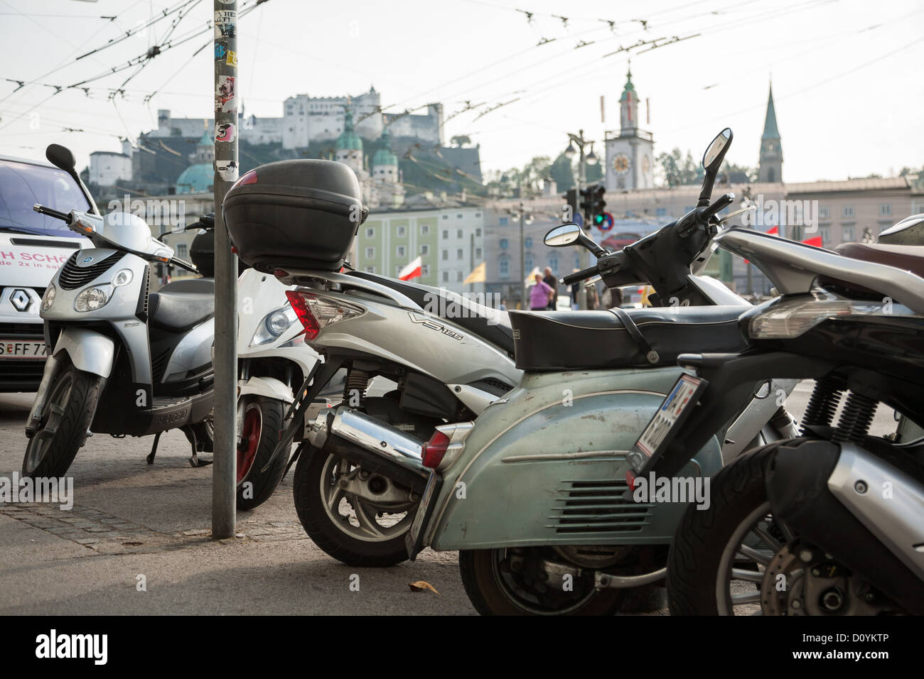 Motos aparcadas en la acera en Salzburgo con la ciudad y el histórico Festung Hohensalzburg muy por encima. Foto de stock