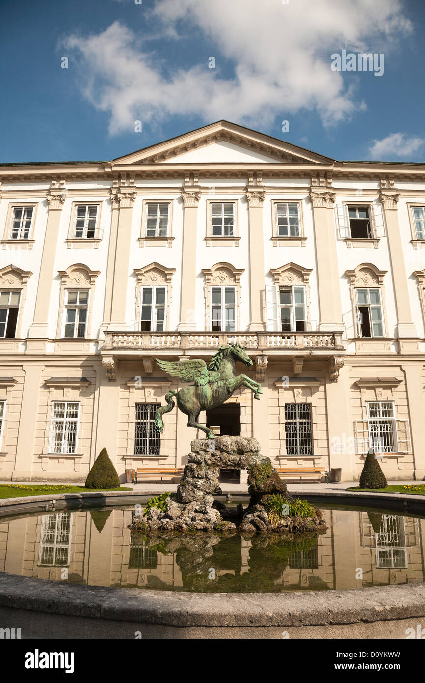 Delante del barroco Palacio Mirabell en Salzburgo con una estatua de bronce de Pegasus en el estanque reflectante y un azul cielo nublado. Foto de stock