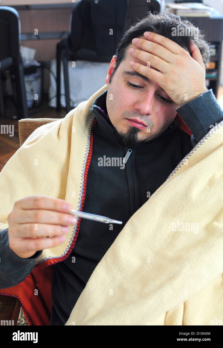 Hombre con gripe comprobando su temperatura Foto de stock
