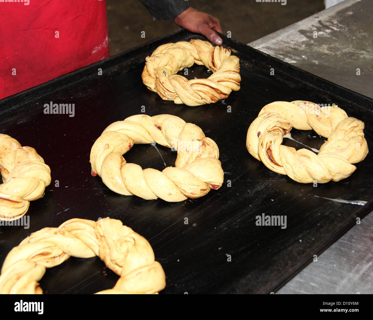 Baker en una panadería industrial con bandeja para hornear dulces y anillos Foto de stock