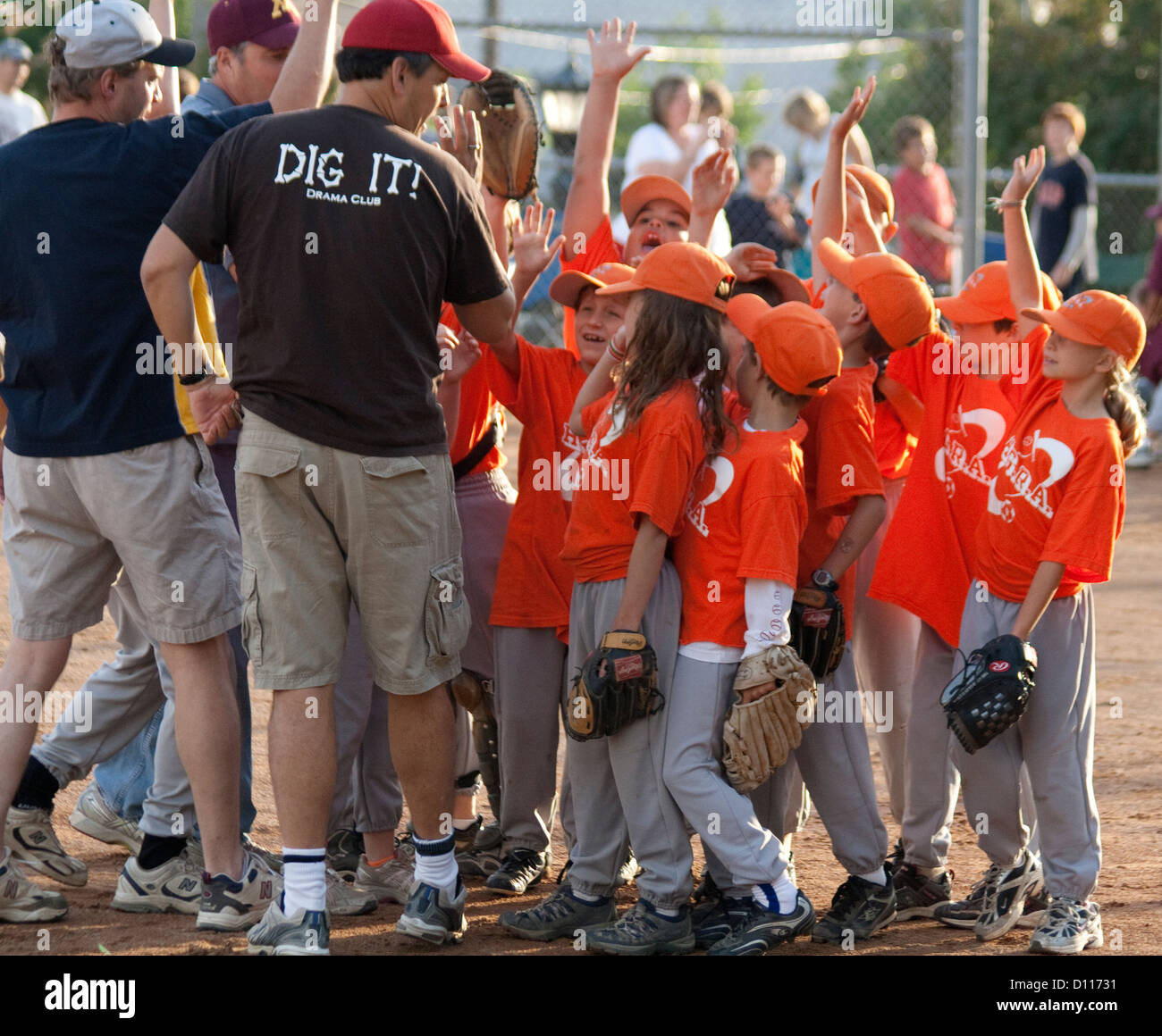 Niños y niñas mixto equipo de béisbol responder a entrenadores con manos levantadas de 7 años de edad. St Paul MN Minnesota EE.UU. Foto de stock