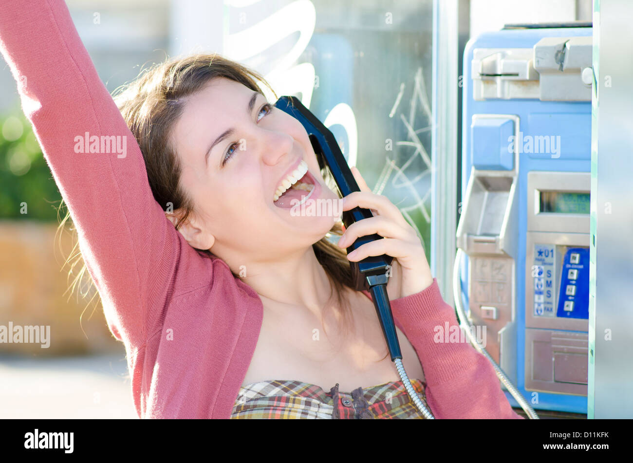 Una mujer alegre y hablando en un teléfono fijo Foto de stock
