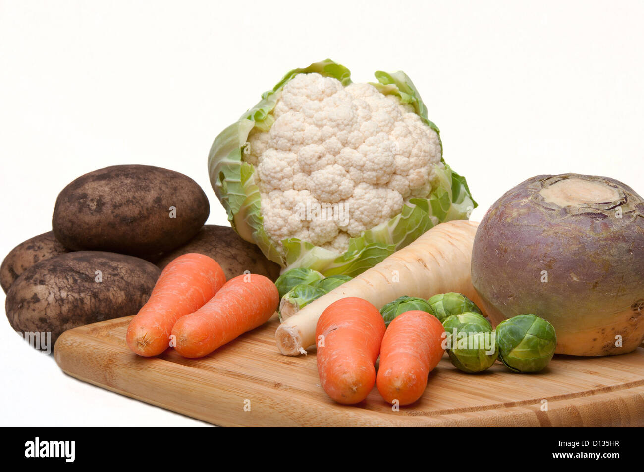 Una selección de hortalizas de invierno incluyendo sueco,alcachofa,zanahorias, Brussel, patatas y coliflor sobre un fondo blanco. Foto de stock