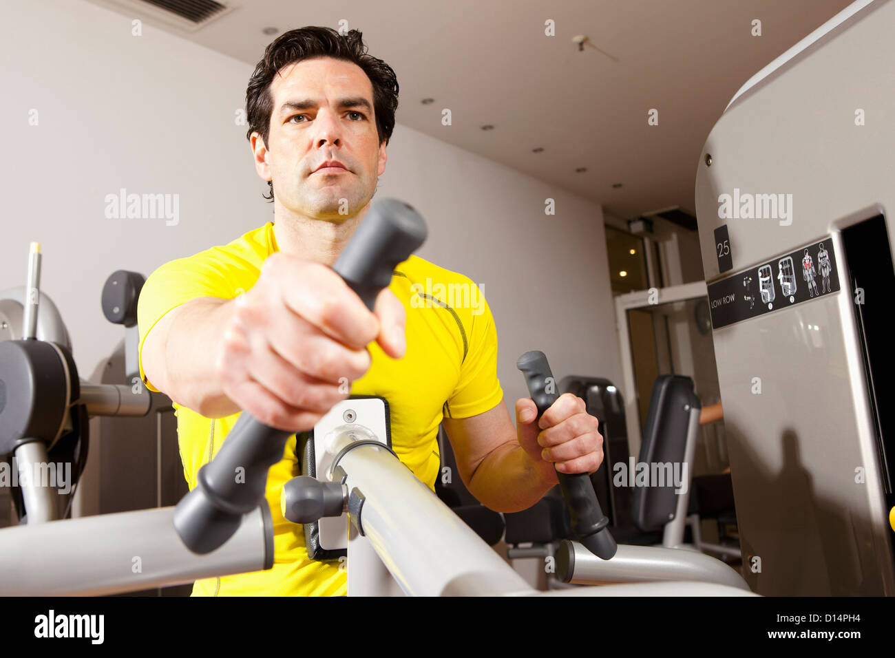 Hombre utilizando equipo de ejercicio en el gimnasio Foto de stock