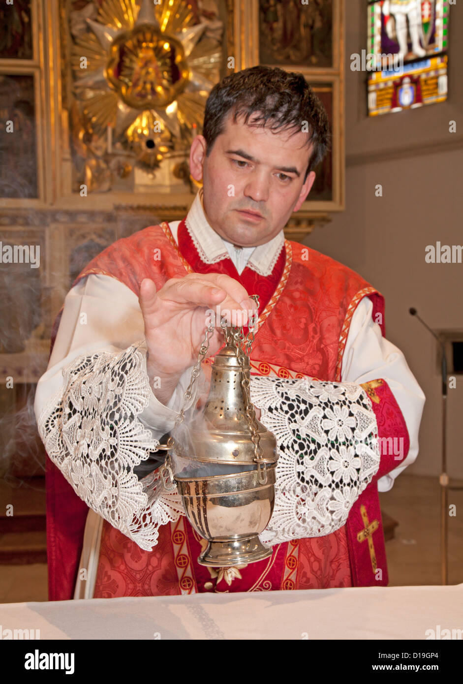El sacerdote católico en el incienso de altar Foto de stock