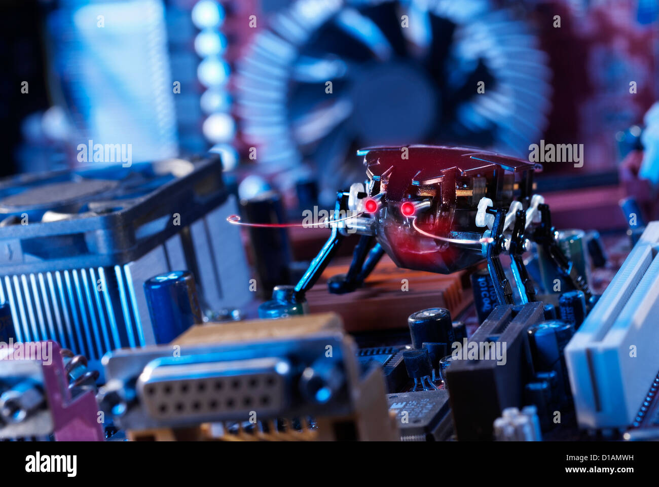 Un robot escarabajo rojo con los ojos brillantes en una motherboard. Foto de stock