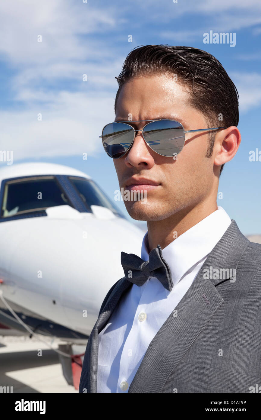 Apuesto joven hombres con gafas de sol avión privado en segundo plano. Foto de stock