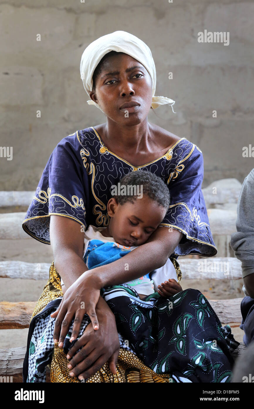 Madre con su hijo dormido (caído enfermos de paludismo) en un banco en una iglesia en Bagamoyo, Tanzania Foto de stock