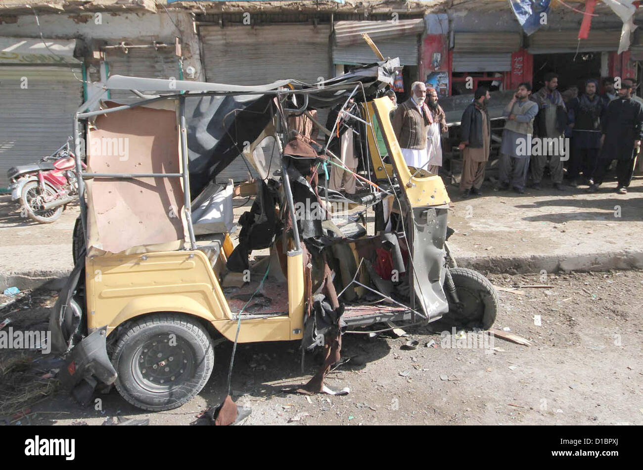 Las personas se reúnen en el sitio después de la explosión como las ruinas visto sentar, en Saryab Road en Quetta el viernes, 14 de diciembre de 2012. Ocho personas heridas incluyendo un oficial de las fuerzas de seguridad, 7Kilgrams bomba fue plantado en un ciclo y destino de tropas militares. Foto de stock