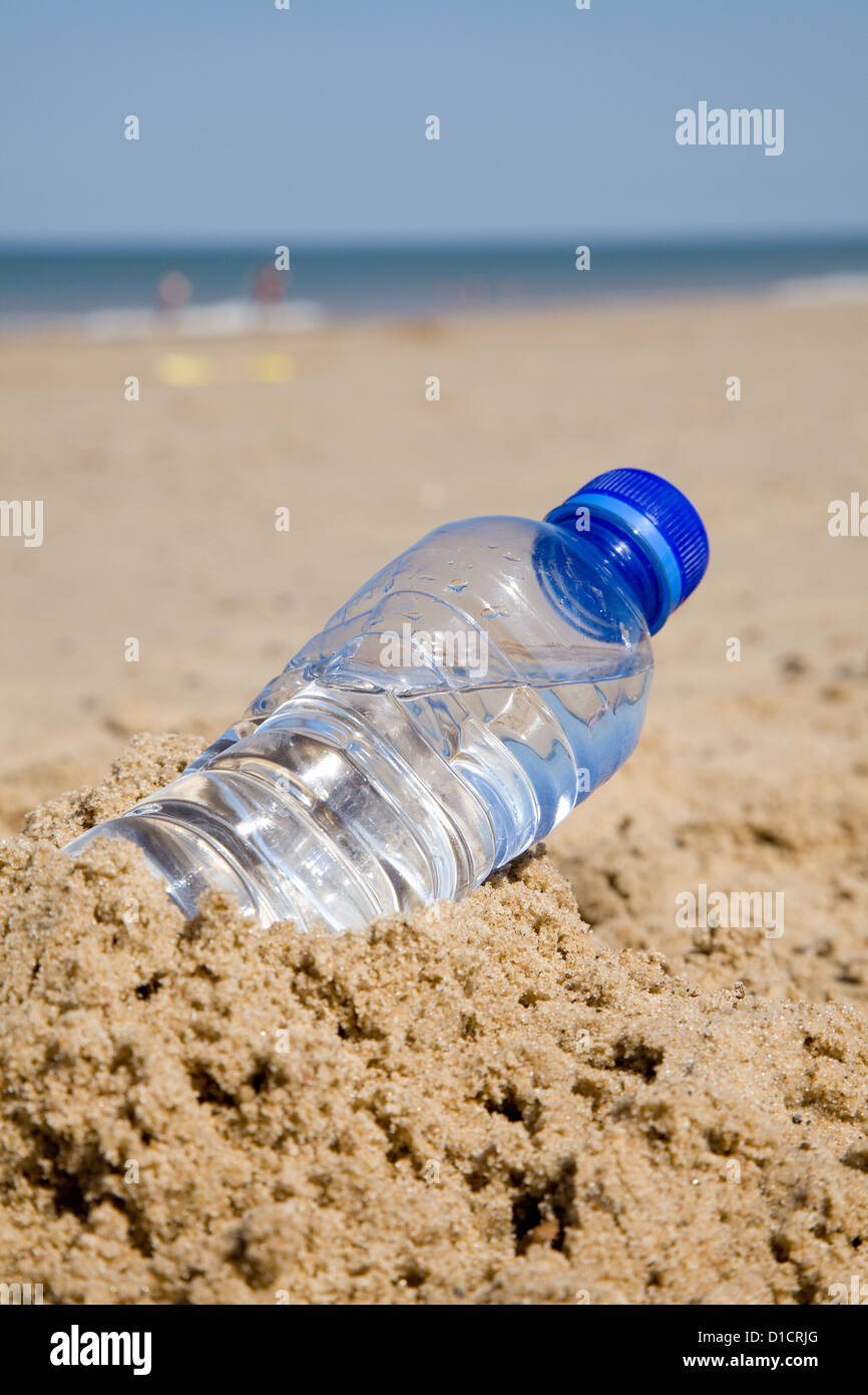 Una botella de plástico a la izquierda detrás en una playa en verano. Foto de stock