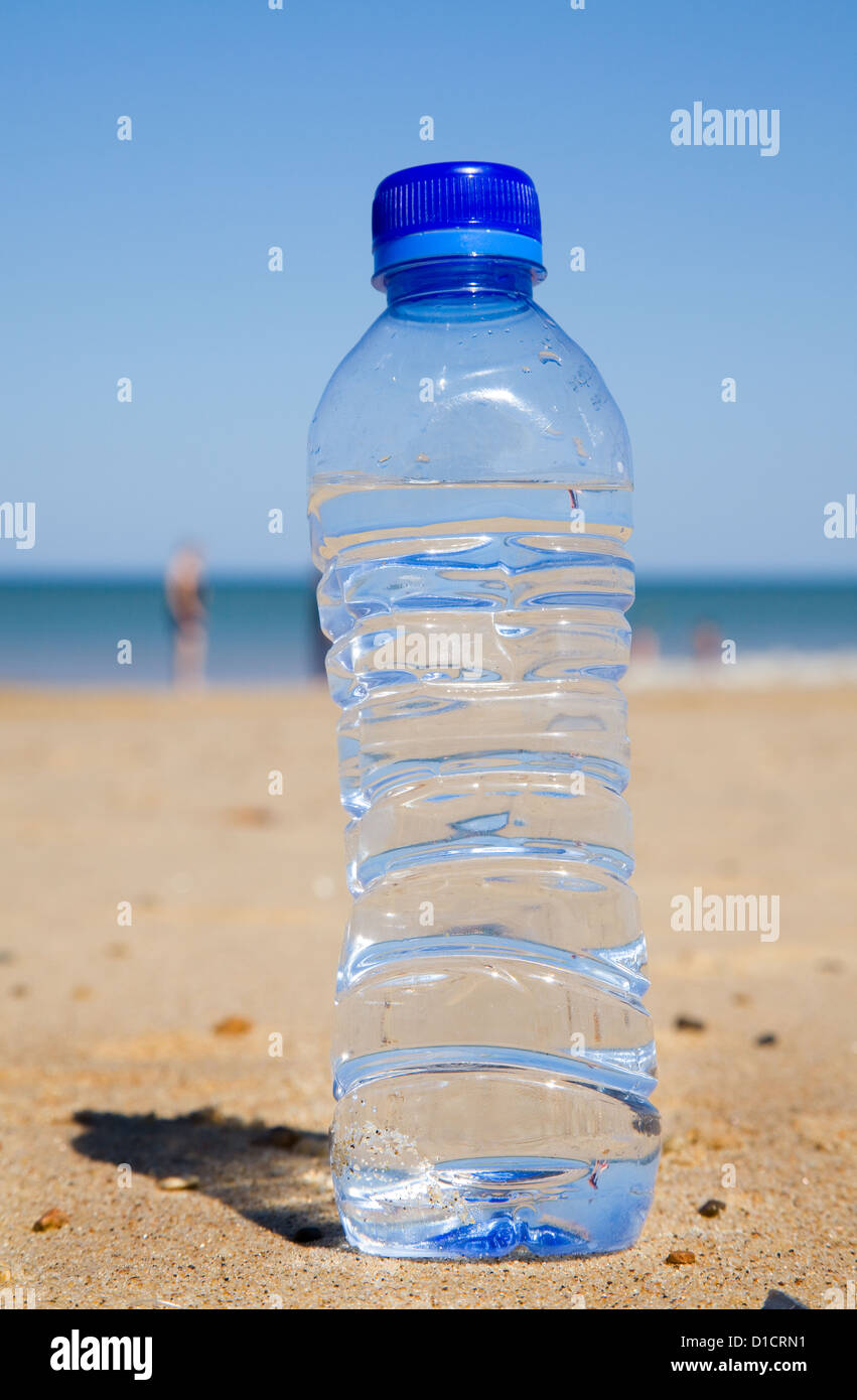 Una botella de plástico a la izquierda detrás en una playa en verano. Foto de stock