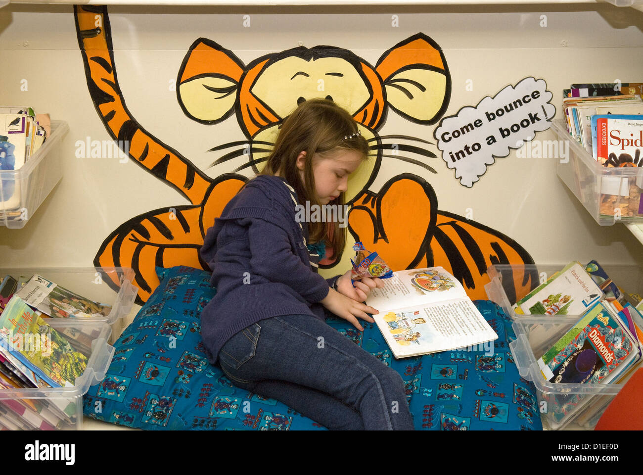 Una niña de 7 años libro de lectura en la escuela primaria, Hampshire, Reino Unido. Foto de stock