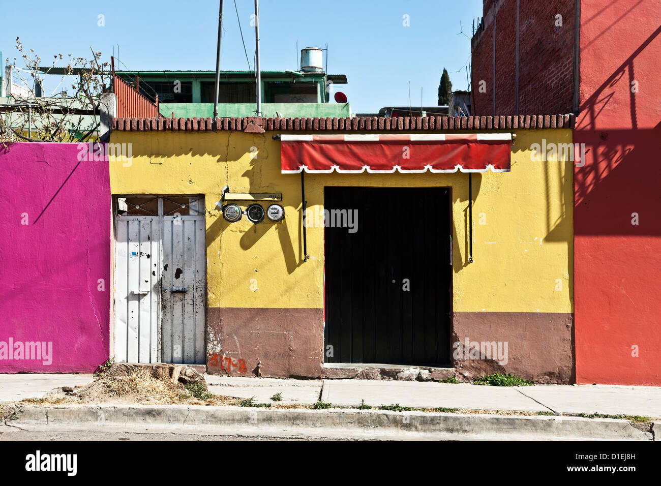 Paisaje urbano edificios pintados con brillantes colores vívidos pintoresco color mexicano con luz solar fuerte en Oaxaca de Juárez en México Foto de stock