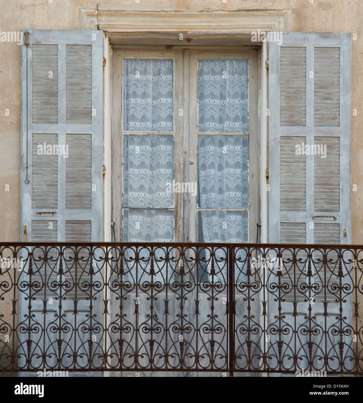 Una vieja ventana, balcón y cortinas en el pintoresco pueblo de Aregno en el interior de la región de Haute Balagne, Córcega, Francia Foto de stock