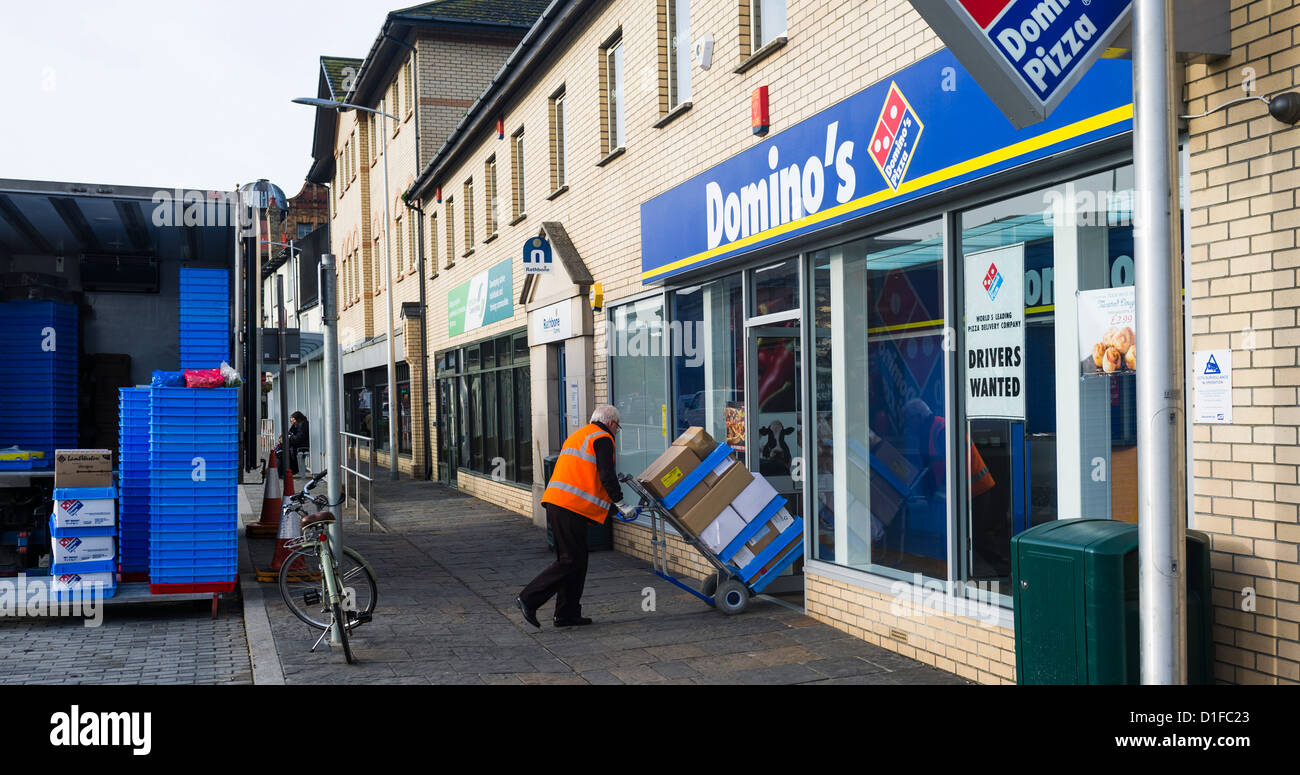 Un hombre entrega de acciones a una sucursal de la franquicia Domino's Pizza, Gales Aberystwyth UK Foto de stock