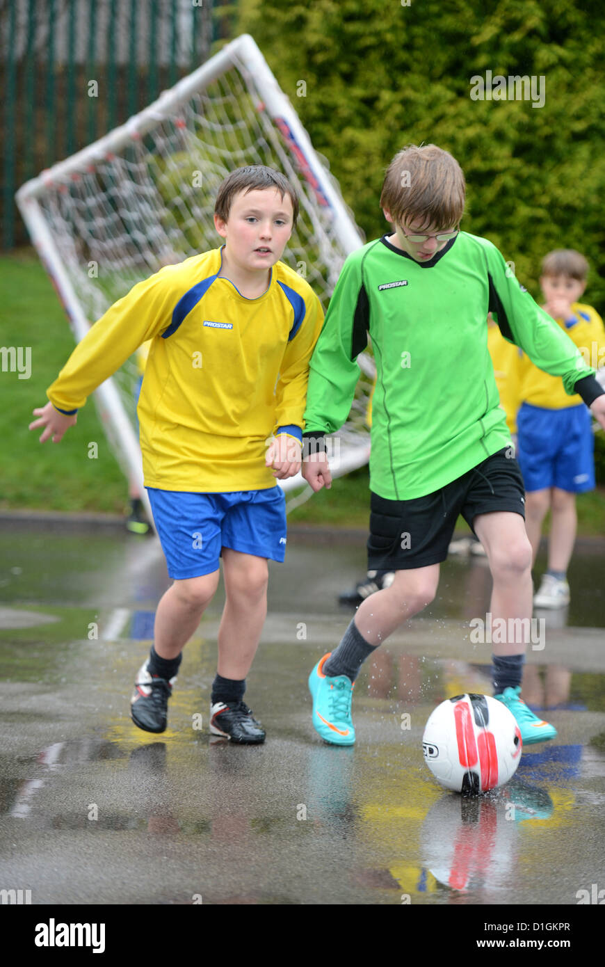 Chicos de escuela de fútbol habilidoso al final de una lluvia fuera práctica coinciden en Nuestra Señora y Santa Werburgh la Escuela Primaria Católica Foto de stock