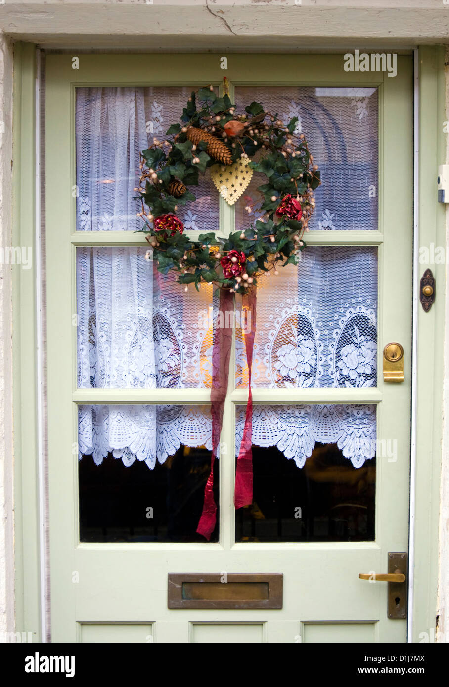Navidad en la puerta delantera con cortinas de encaje Foto de stock