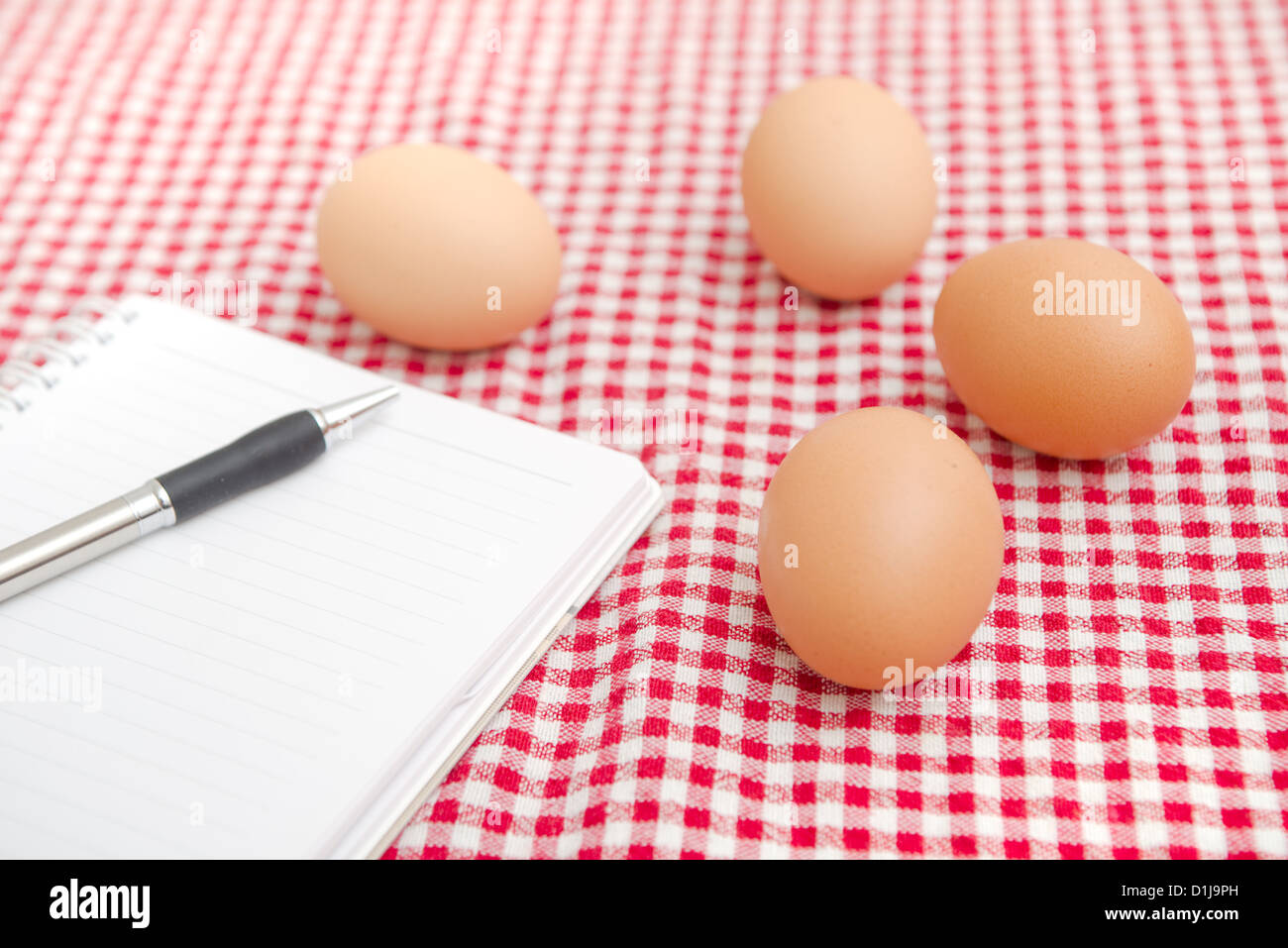 Los huevos de gallina sobre la mesa con manteles a cuadros rojos y blancos. Foto de stock