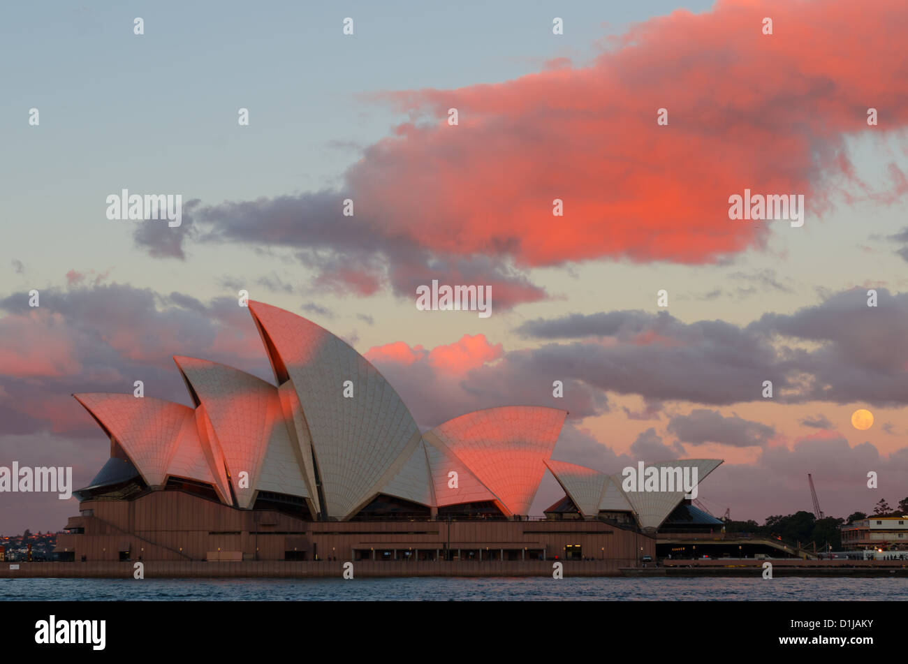 Sydney Opera House al atardecer iluminado y Luna a la izquierda Foto de stock