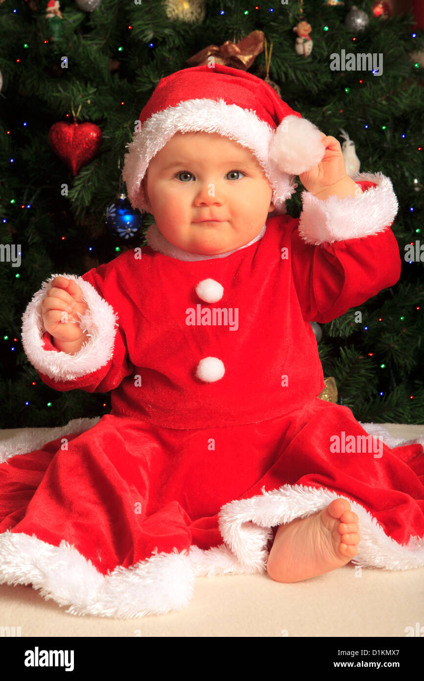 Bebé de 8 meses niña vestidos como Santa Claus delante de un árbol de  Navidad Fotografía de stock - Alamy