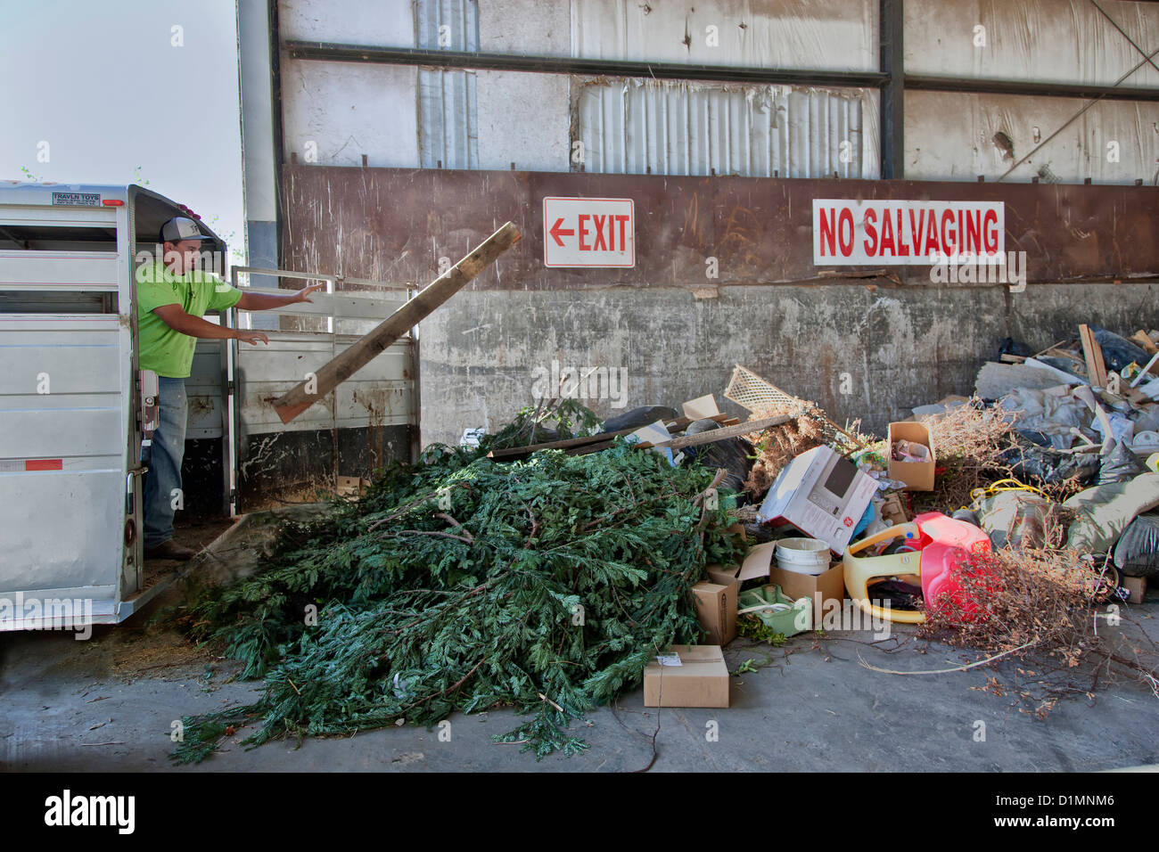 Macho adulto joven dumping trash & plásticos del remolque, sitio de recogida. Foto de stock