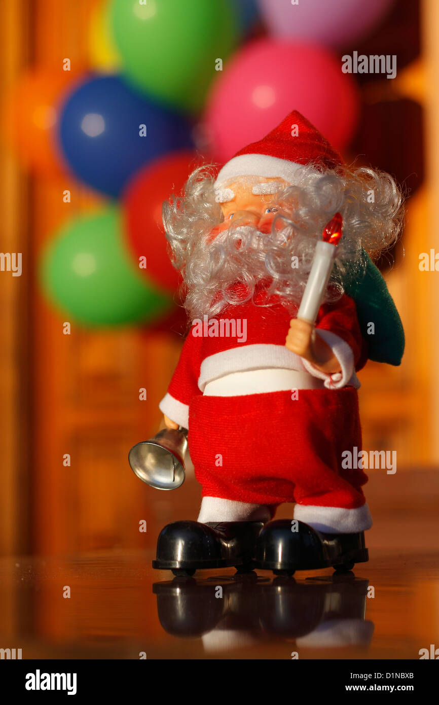 Un poco de Santa Claus toy delante un colorido grupo de fuera de foco de los globos. Foto de stock