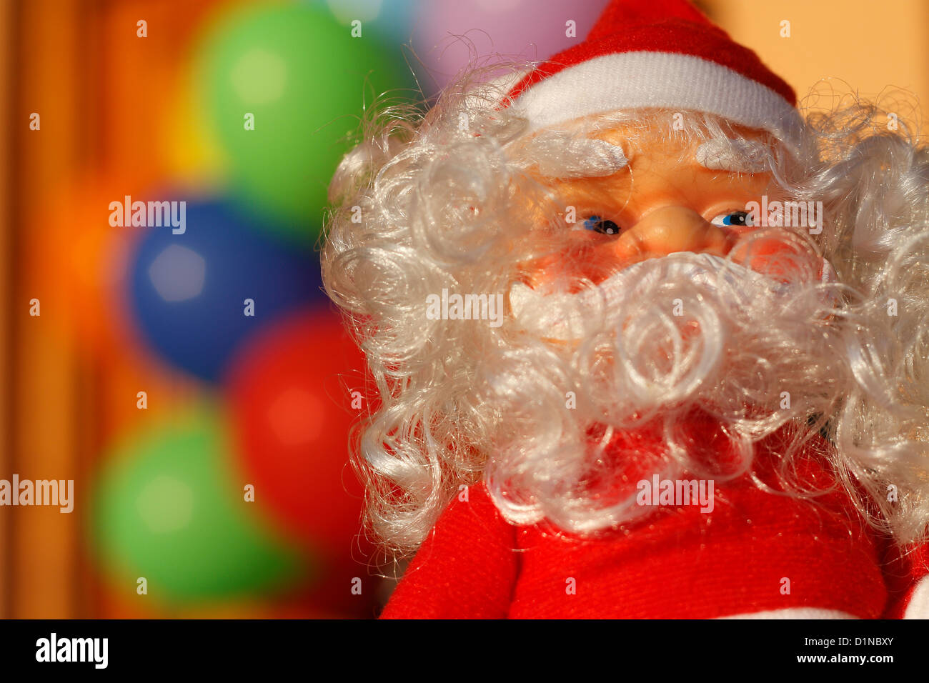 Un poco de Santa Claus toy delante un colorido grupo de fuera de foco de los globos. Foto de stock