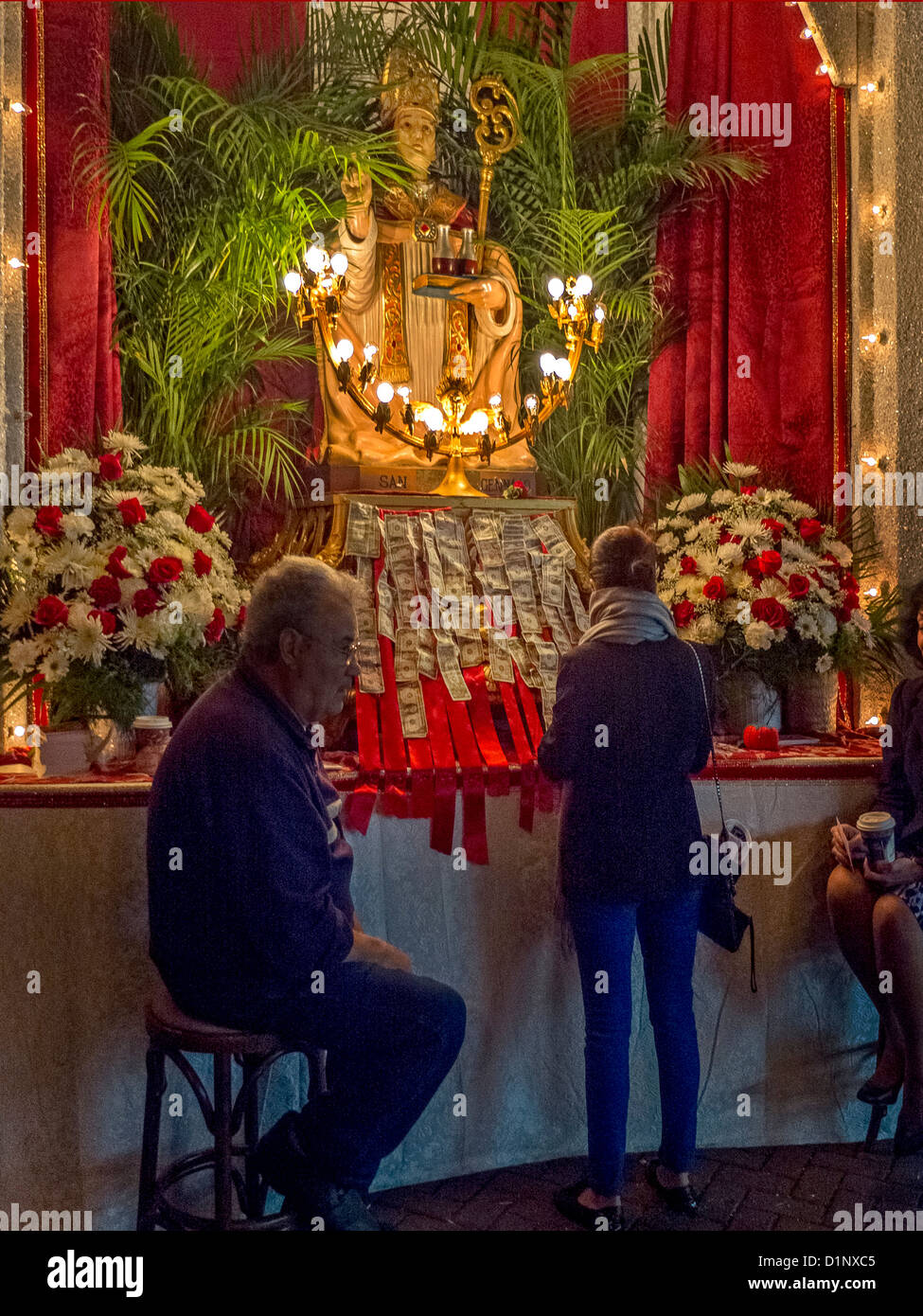Una mujer hace una contribución a un santo católico en un santuario al aire libre en la Ciudad de Nueva York de 'Little Italy' en el festival de la calle. Foto de stock