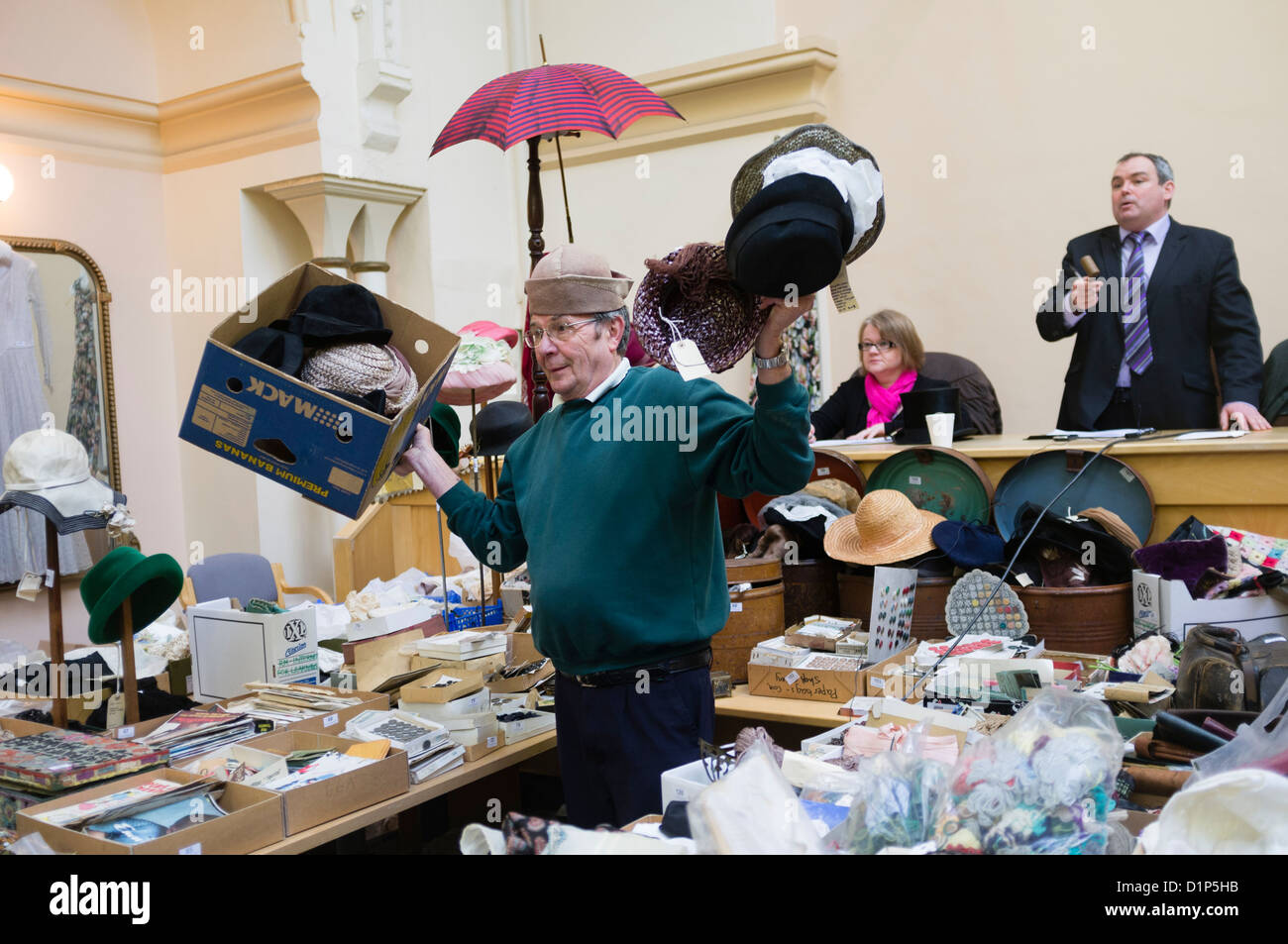 Un ayudante sujetando los sombreros en venta en una subasta de antigüedades, ropa y Bric-a-Brac, UK Foto de stock