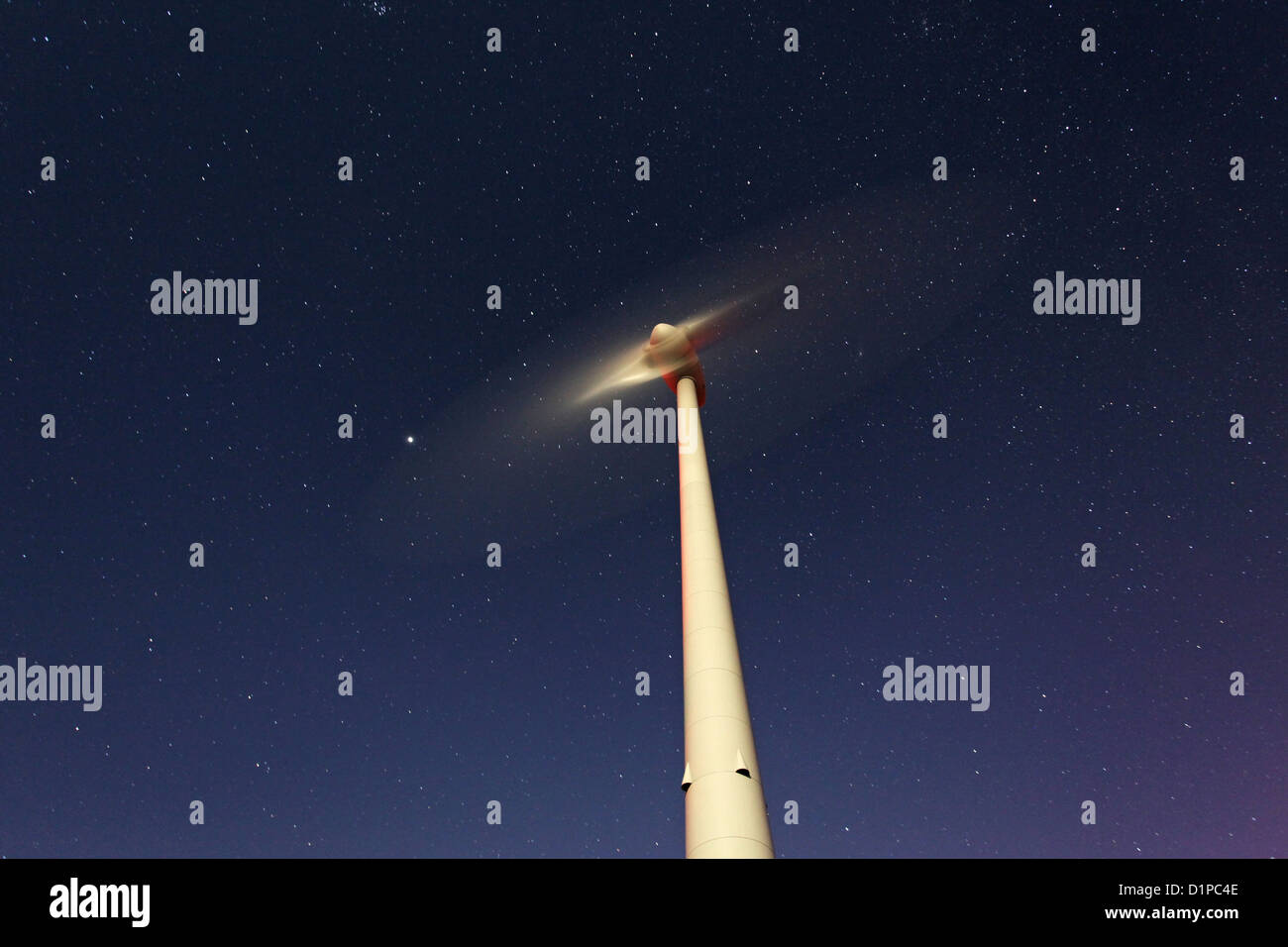 El movimiento de las paletas de las turbinas eólicas bajo un cielo estrellado en una noche de luna llena Foto de stock