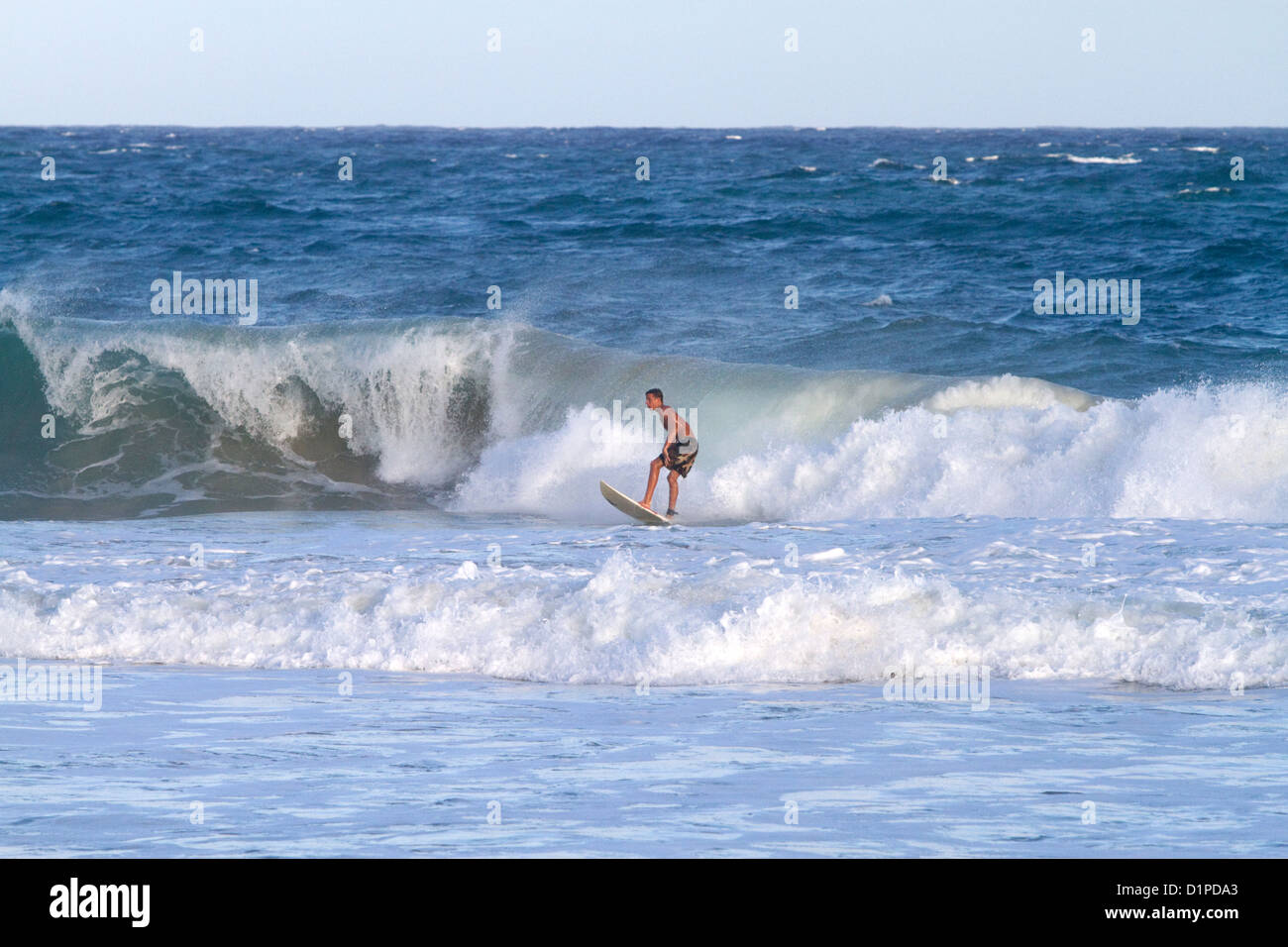 Surfer montando las olas del océano Pacífico frente a la costa de la isla de Kauai, Hawaii, USA. Foto de stock