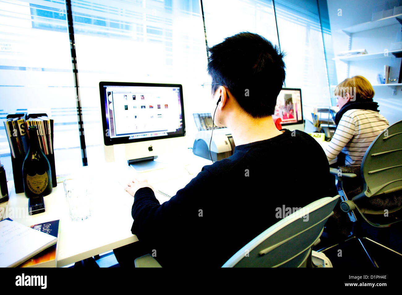 Las espaldas de 2 jóvenes diseñadores gráficos trabajan en equipos en una oficina. Foto de stock