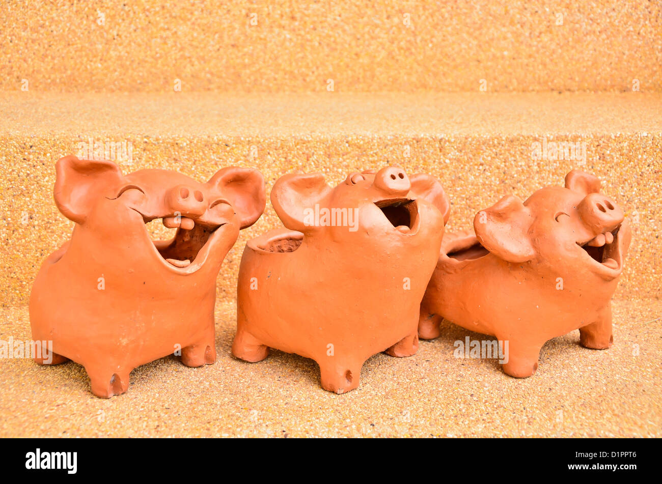 Tres estatuas de cerdo reír hacia el mismo lado. Foto de stock