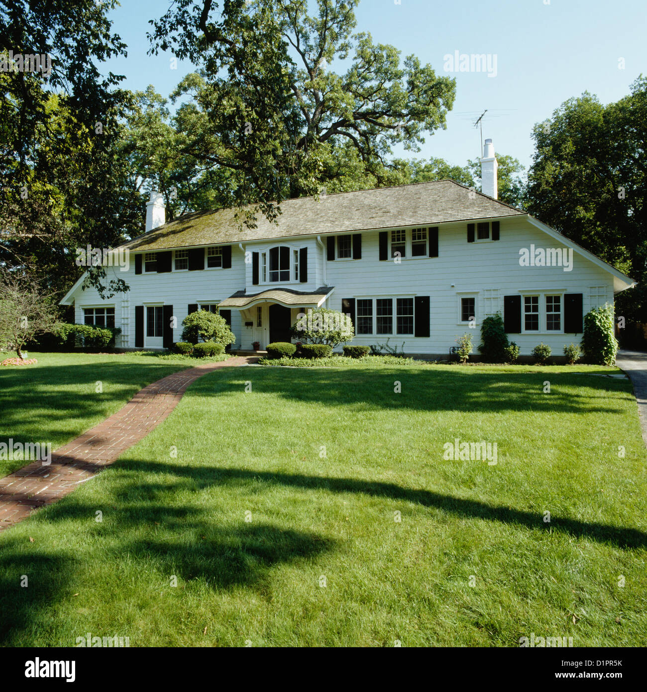 Exteriores: gran simétrico elegante marco blanco house, gran césped delantero con pasarela de ladrillo Foto de stock
