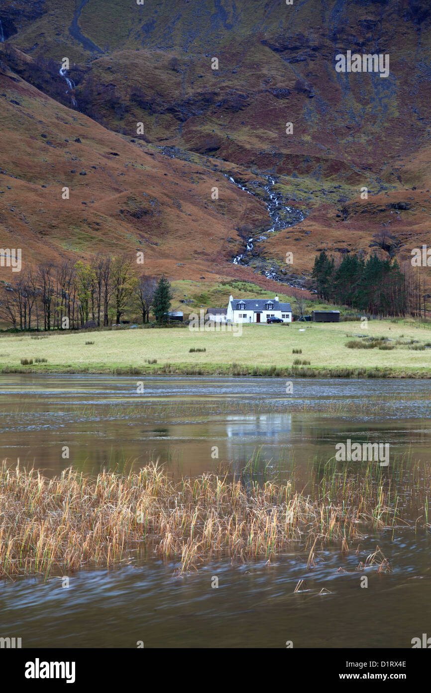 Loch Achtriochtan Glencoe Escocia pequeña casita blanca en la base de un cayó. Foto de stock