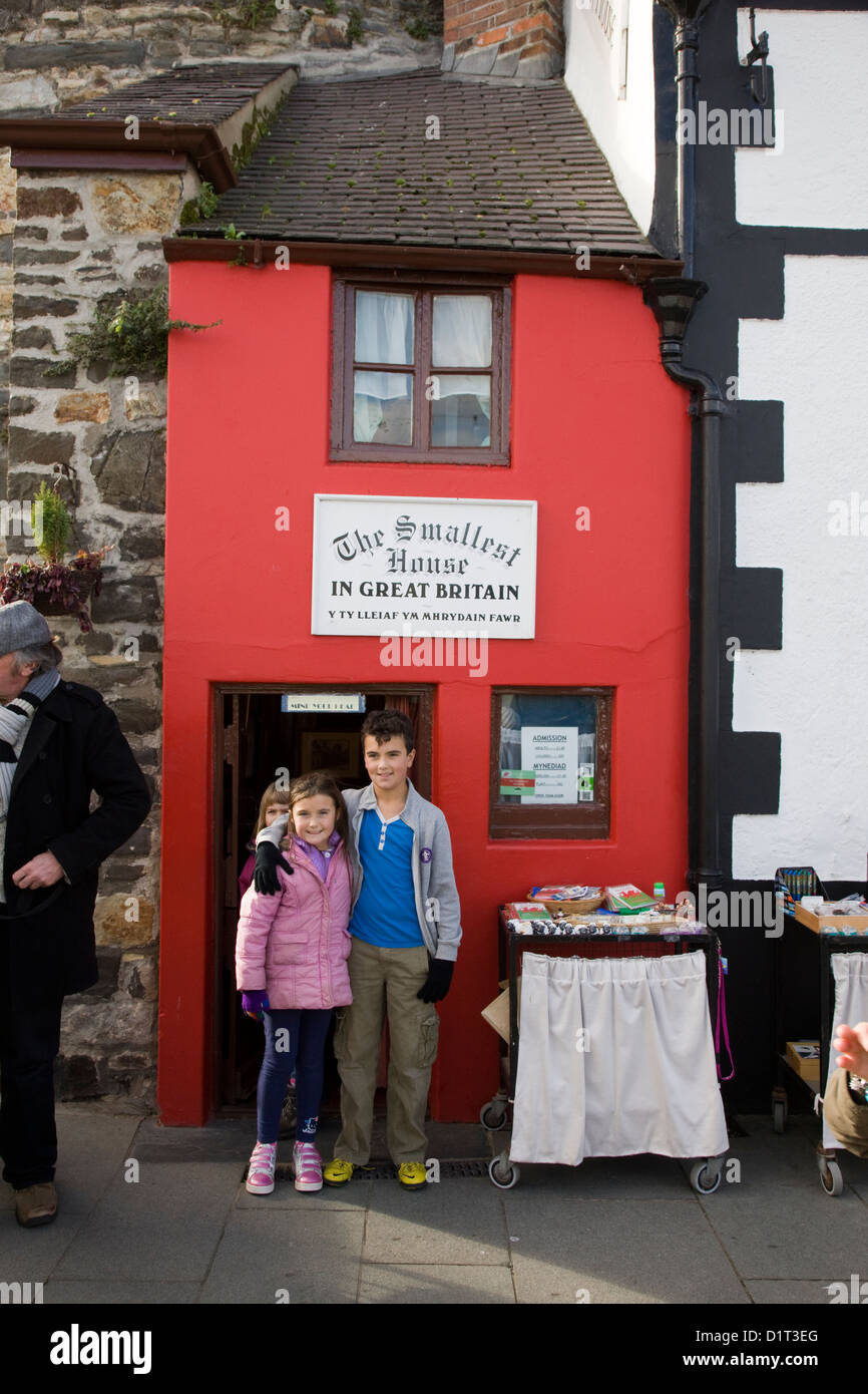Los niños posan para una fotografía fuera de la casa más pequeña de Gran Bretaña, Conwy, Gales Foto de stock
