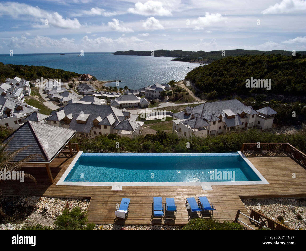 Una piscina de borde infinito bajo un cielo azul en un resort en la isla de Antigua en el Caribe. Foto de stock